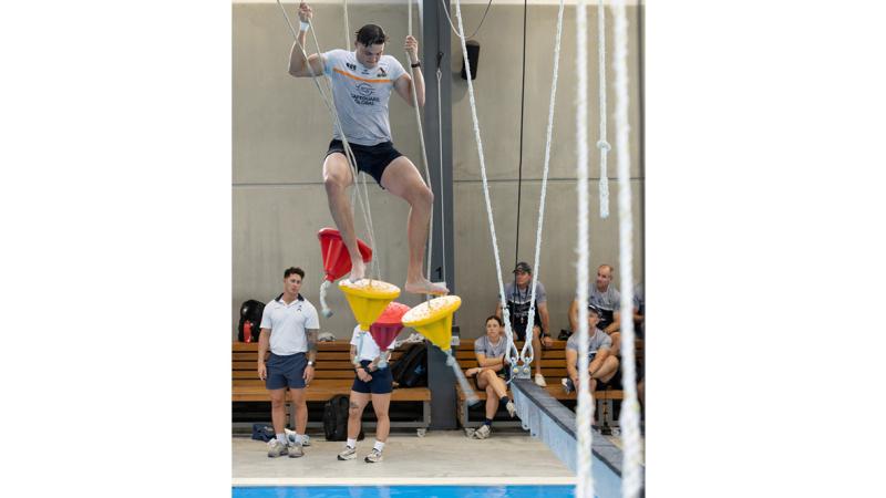 Petty Officer Corey Evans, left, supervises as Tom Hooper of the ACT Brumbies Super Rugby Pacific Squad negotiates the overwater obstacle course at HMAS Creswell gymnasium, Jervis Bay.