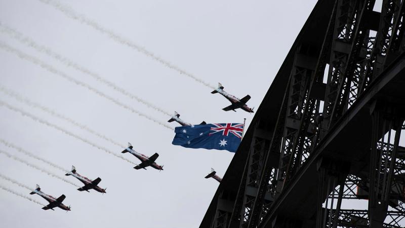 Air Force Roulettes fly in formation with an Australian flag over the Sydney Harbour Bridge.