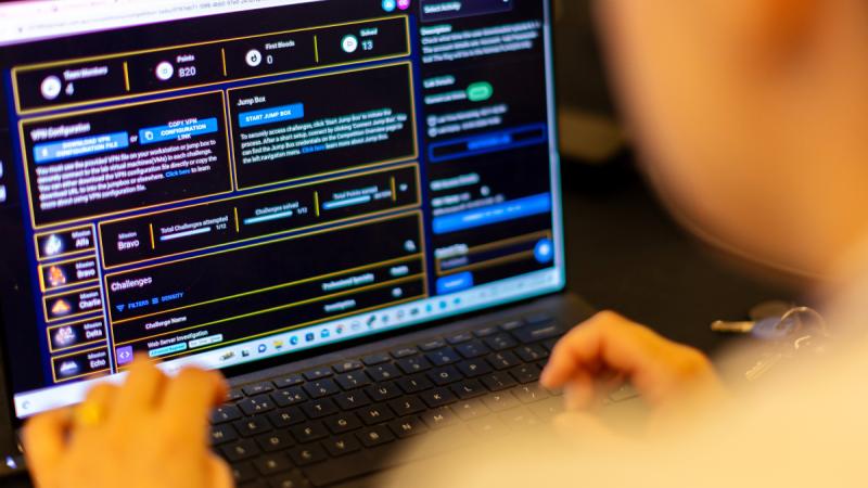 A person gaming on a laptop, viewed from over their shoulder.