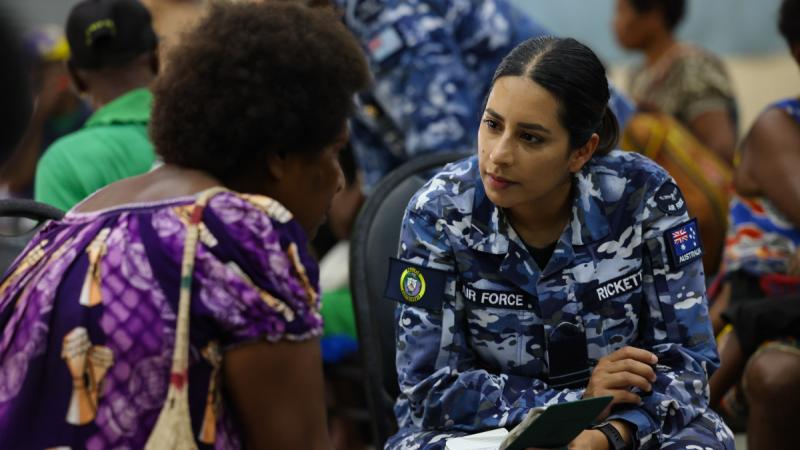 A woman in Royal Australian Air Force uniform speaks with local woman at a workshop in Papua New Guinea.
