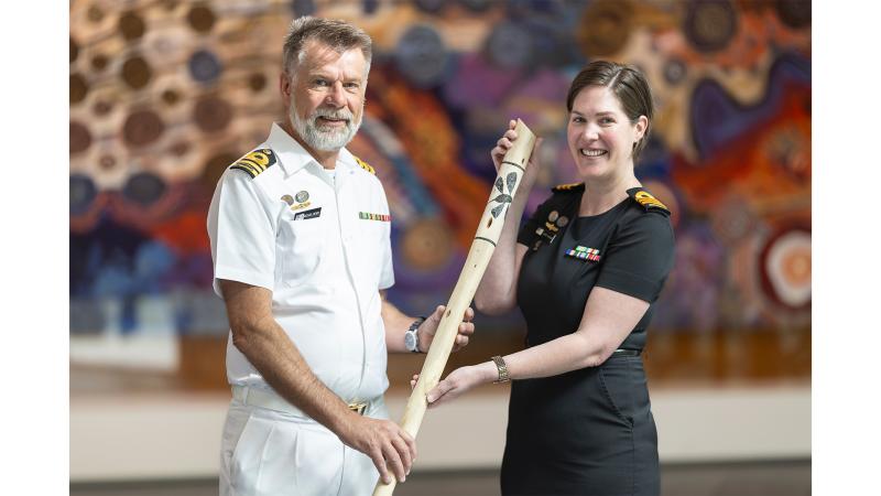 A man and woman in military uniform with a decorated stick.